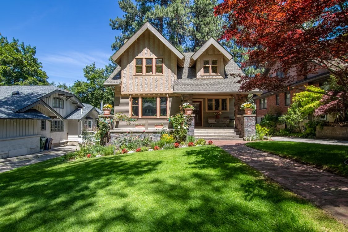 Craftsman home with a landscaped garden, mature trees, and a covered front porch